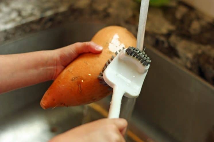 scrubbing sweet potatoes to prepare for cooking